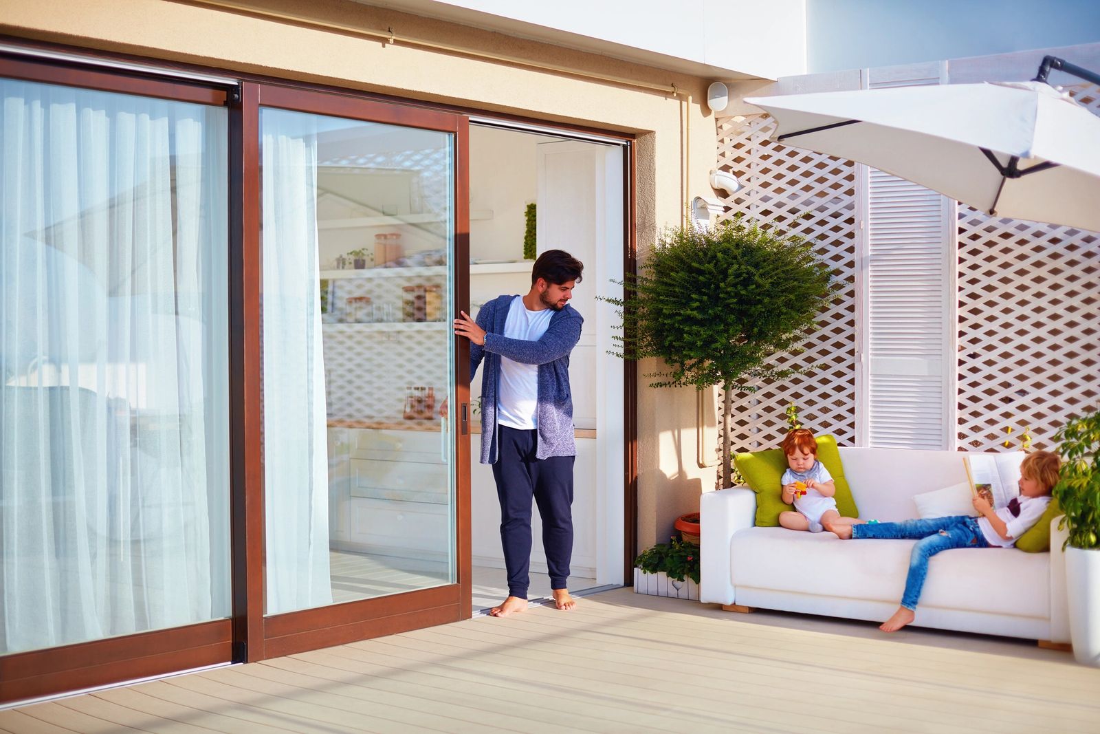 Family relaxing on a patio with open sliding glass doors